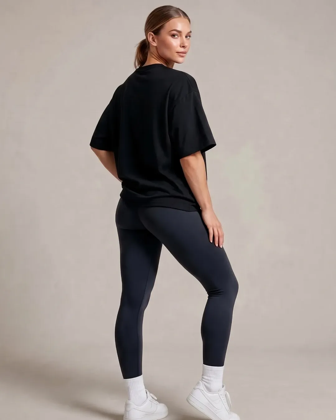 Female model wearing the black SQUATRAT SR-T-003 minimalist oversized T-shirt, full-length back view.