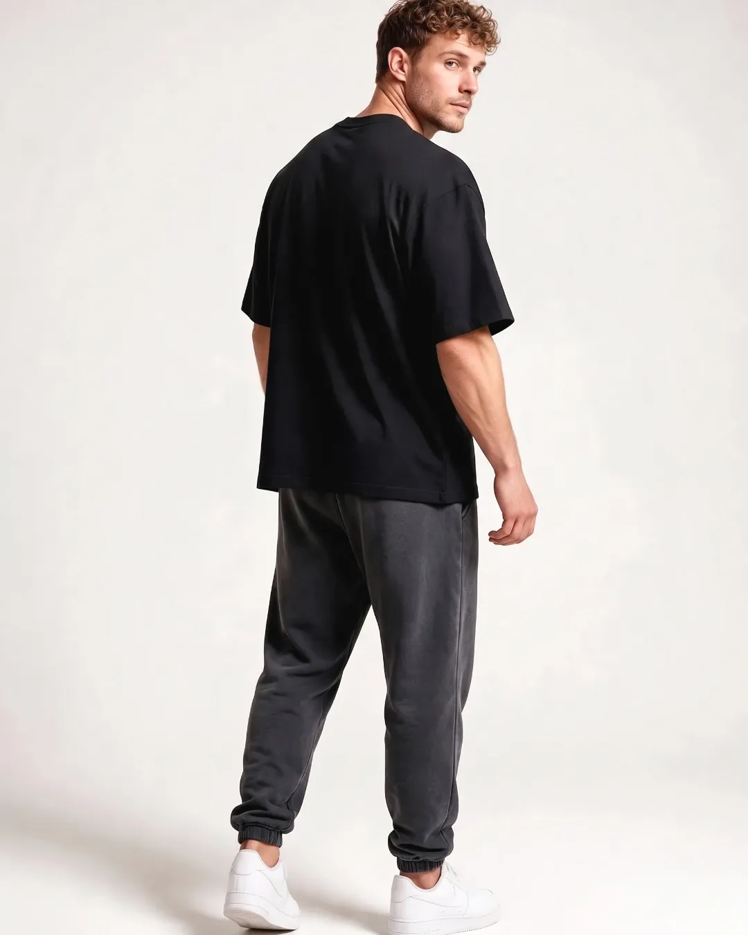 Male model wearing the black SQUATRAT SR-T-003 minimalist oversized T-shirt, full-length back view.